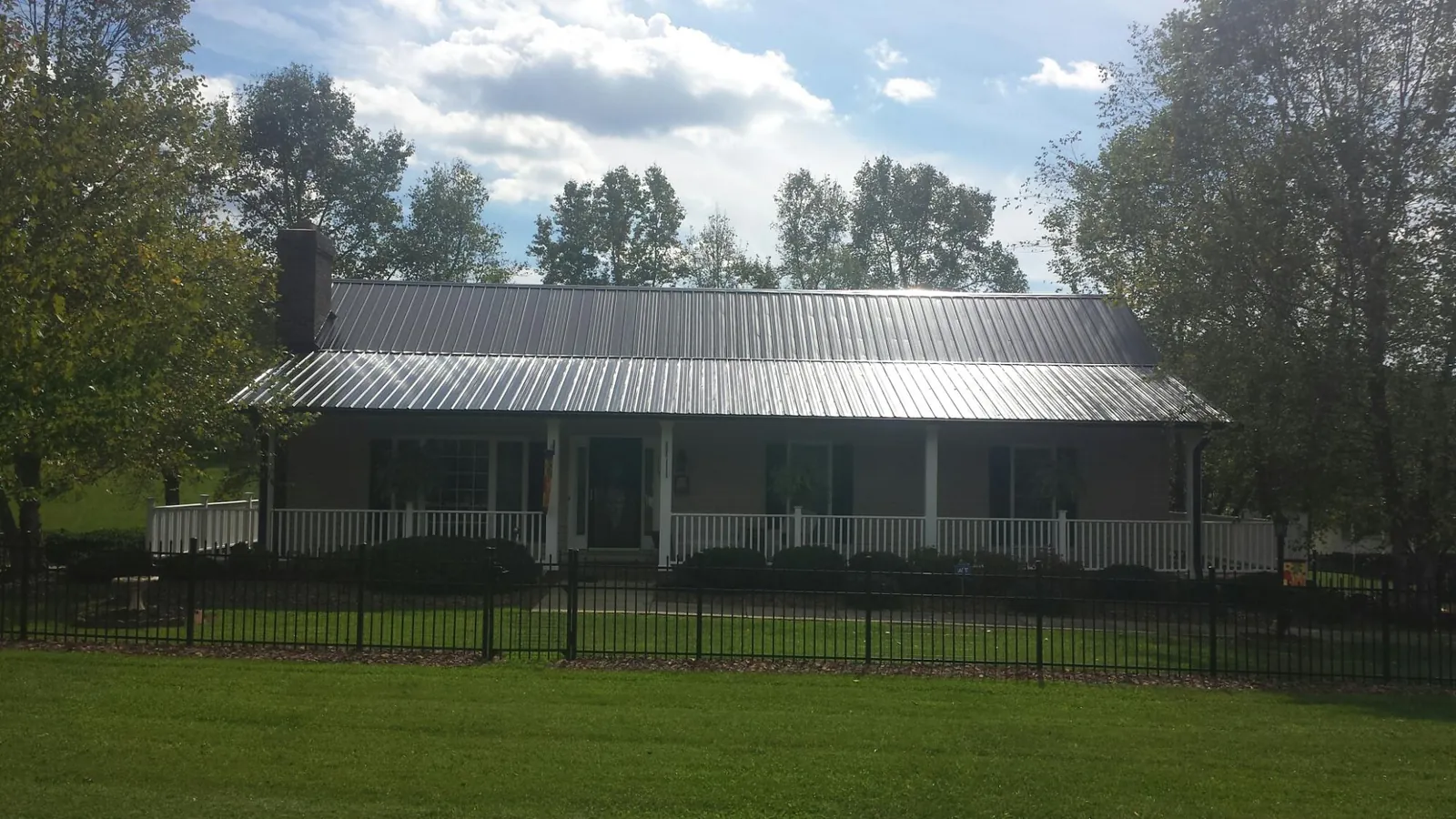 Gray metal roof on a brick ranch with a full width front porch — Gutter Guard Installation work by our crew in Pell Lake