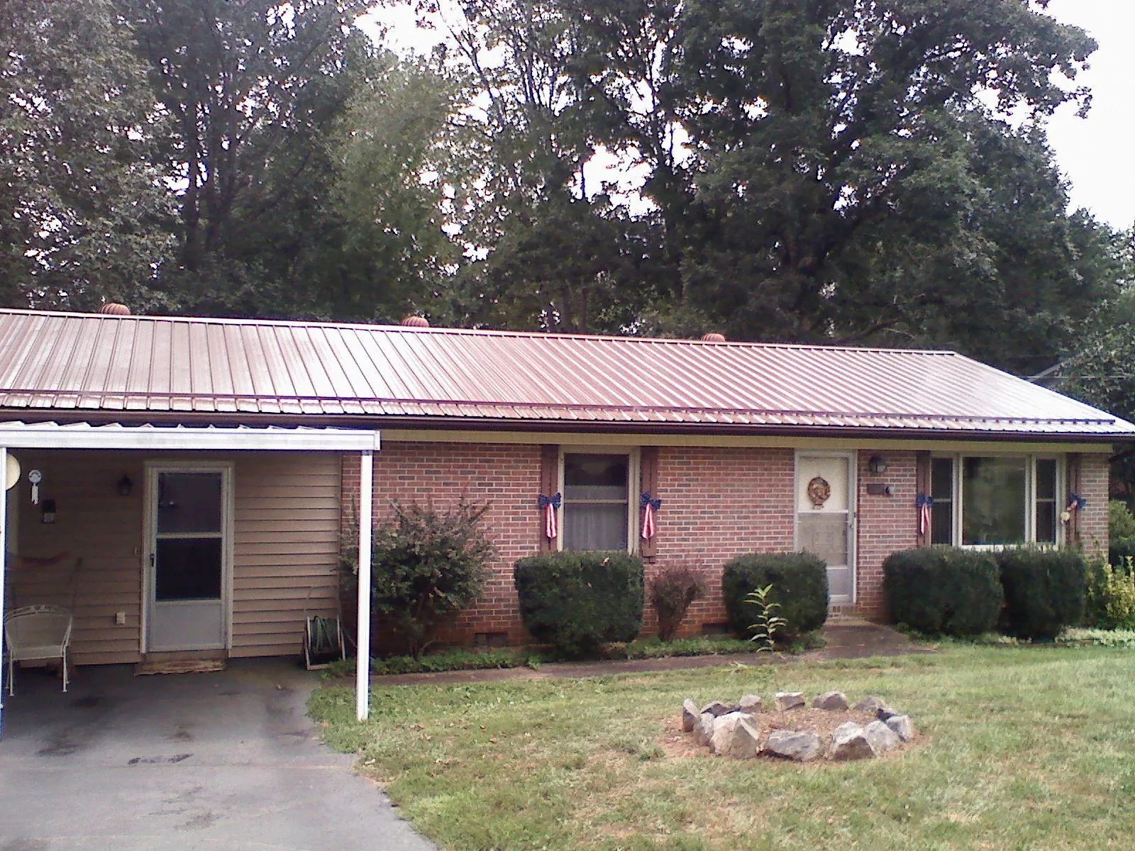 Bronze metal roof and carport on a brick ranch home — Roof Repair work by our crew in Pell Lake
